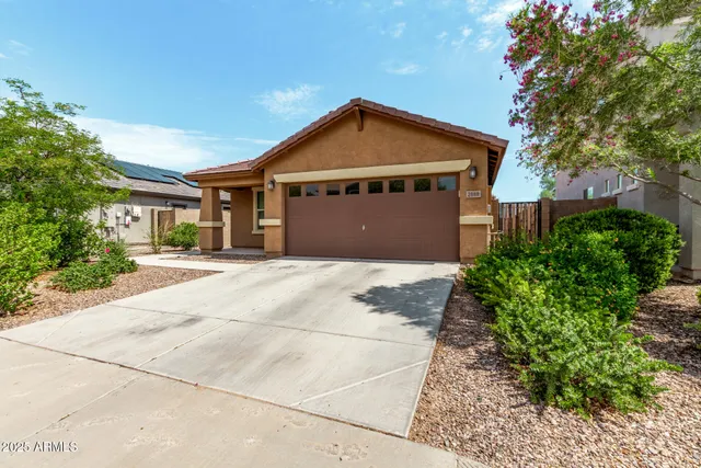 a view of an empty room and kitchen view with wooden floor