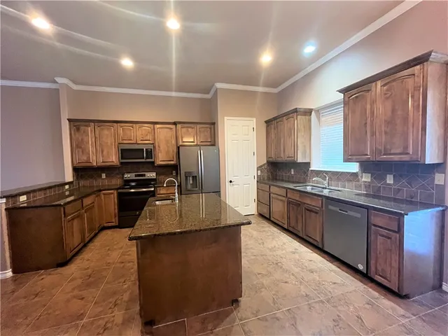a large kitchen with granite countertop lots of counter top space a sink and stainless steel appliances