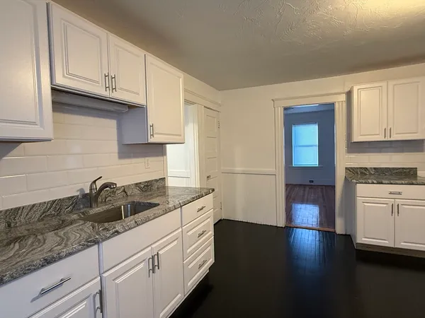 a kitchen with granite countertop a sink a stove and cabinets