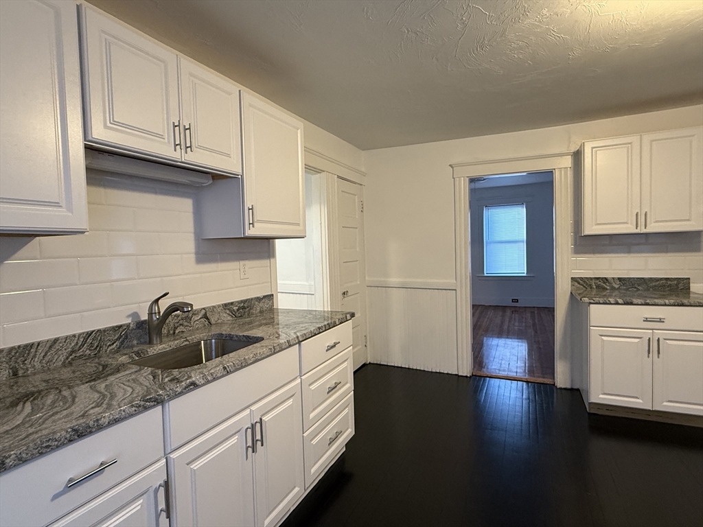 a kitchen with granite countertop a sink a stove and cabinets