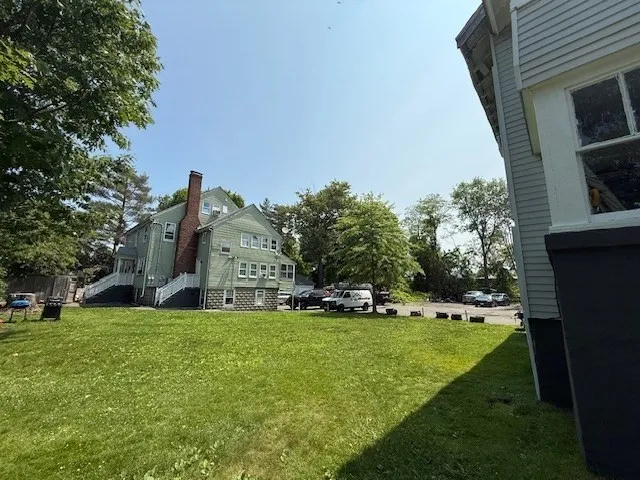a view of a house with a big yard and large trees