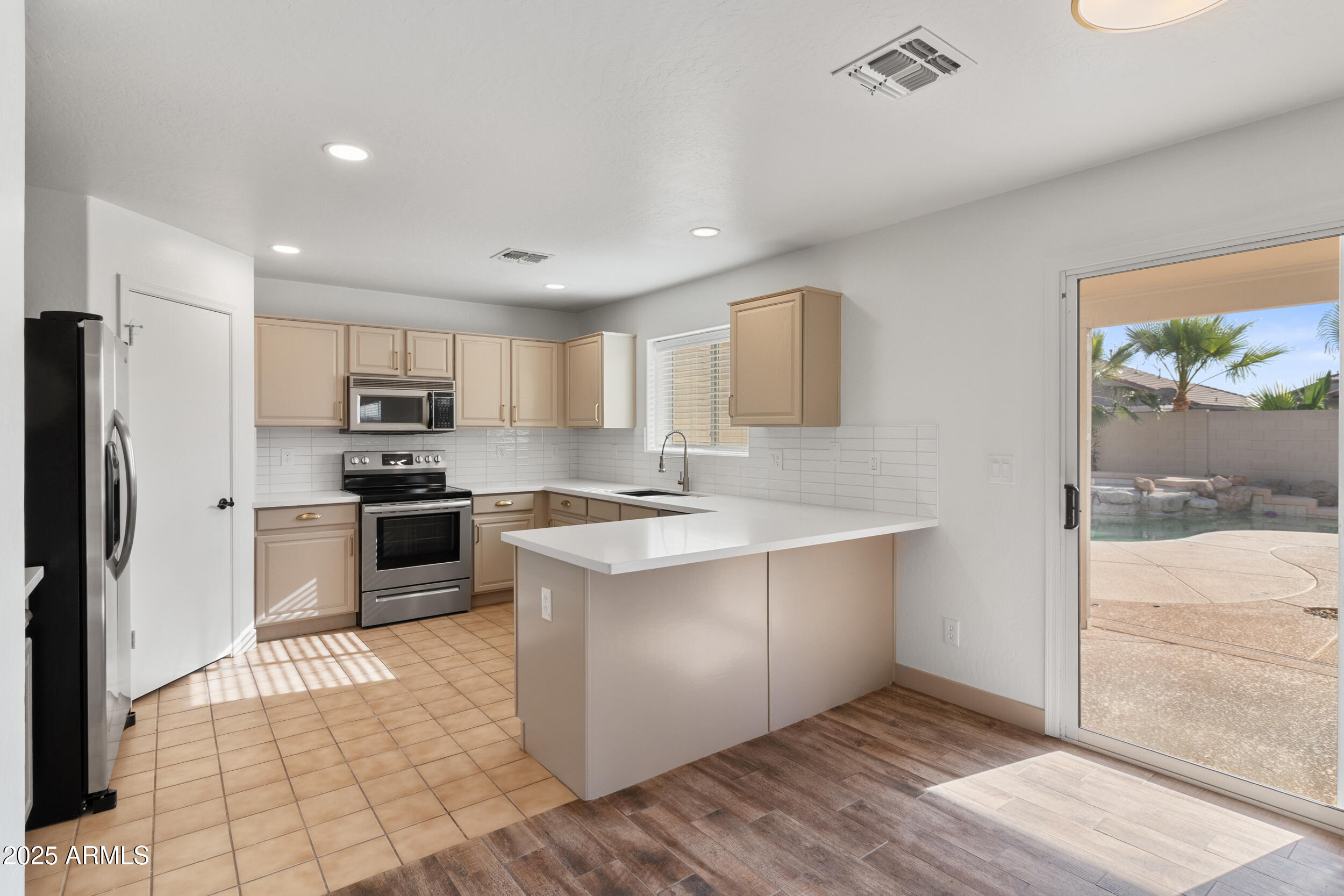 16329 West Rimrock Street Surprise, AZ 85388 - Photo 11 of 31 a large kitchen with a large counter top stainless steel appliances and cabinets