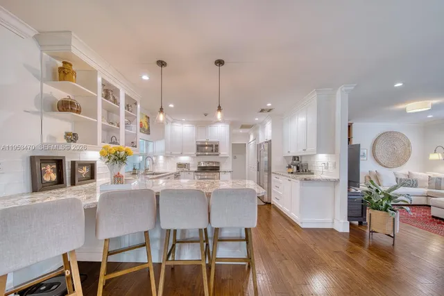 a kitchen with stainless steel appliances kitchen island granite countertop a dining table chairs and white cabinets