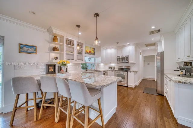 a kitchen with stainless steel appliances a dining table chairs stove refrigerator and cabinets