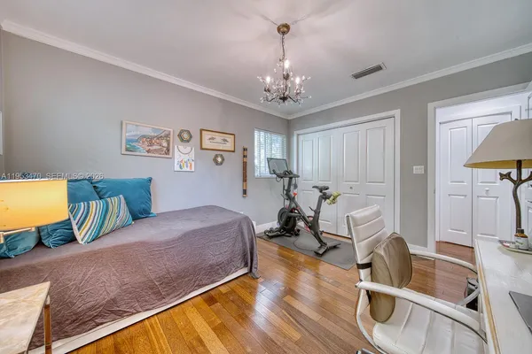 a spacious bedroom with a bed a chandelier and a dresser
