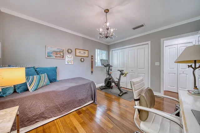 a spacious bedroom with a bed a chandelier and a dresser