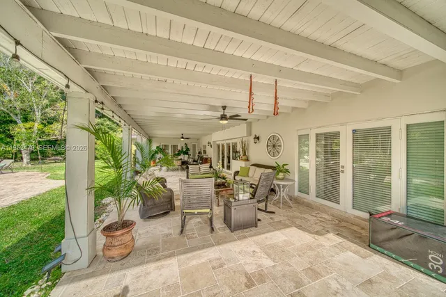 a view of a patio with table and chairs potted plants and floor to ceiling window