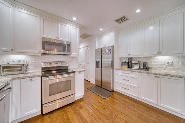 a kitchen with stainless steel appliances granite countertop a stove a refrigerator and a microwave