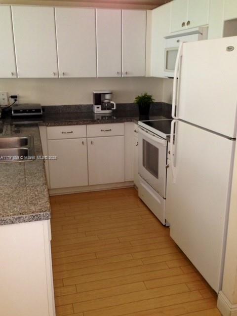 2740 Southwest 28th Terrace, Unit 304 Miami, FL 33133 - Photo 6 of 13 a kitchen with granite countertop a white cabinets and white appliances