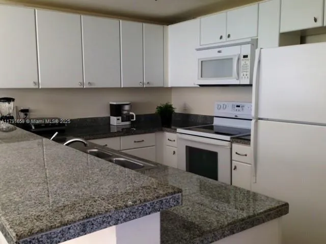 a kitchen with stainless steel appliances granite countertop a sink stove and white cabinets
