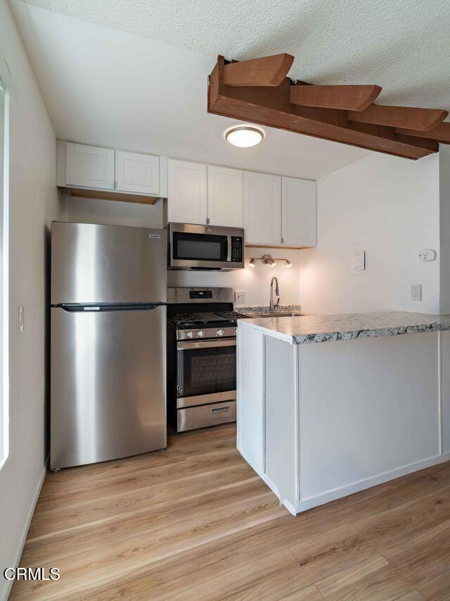 1925 Ginger Street, Unit 104 Oxnard, CA 93036 - Photo 5 of 25 a kitchen with granite countertop a refrigerator and a stove top oven