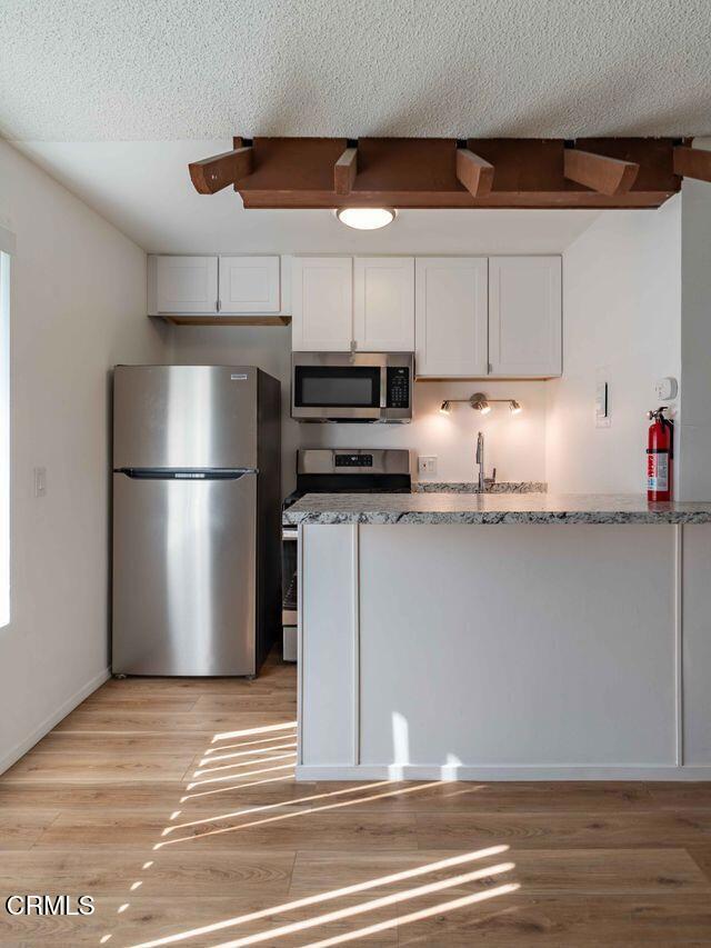 1925 Ginger Street, Unit 104 Oxnard, CA 93036 - Photo 7 of 25 a kitchen with granite countertop a refrigerator and a stove top oven