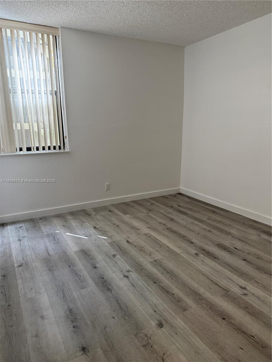 20441 Northeast 30th Avenue, Unit 1129 Aventura, FL 33180 - Photo 11 of 16 a view of an empty room with wooden floor and a window