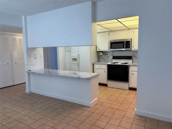 a living room with stainless steel appliances kitchen island granite countertop a refrigerator and a stove top oven