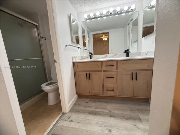 a spacious bathroom with a sink a toilet a mirror and shower
