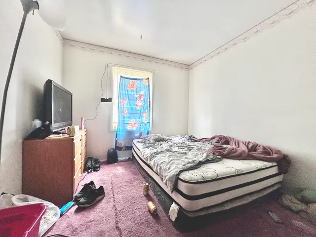 a bedroom with a bed and a flat tv screen on dresser