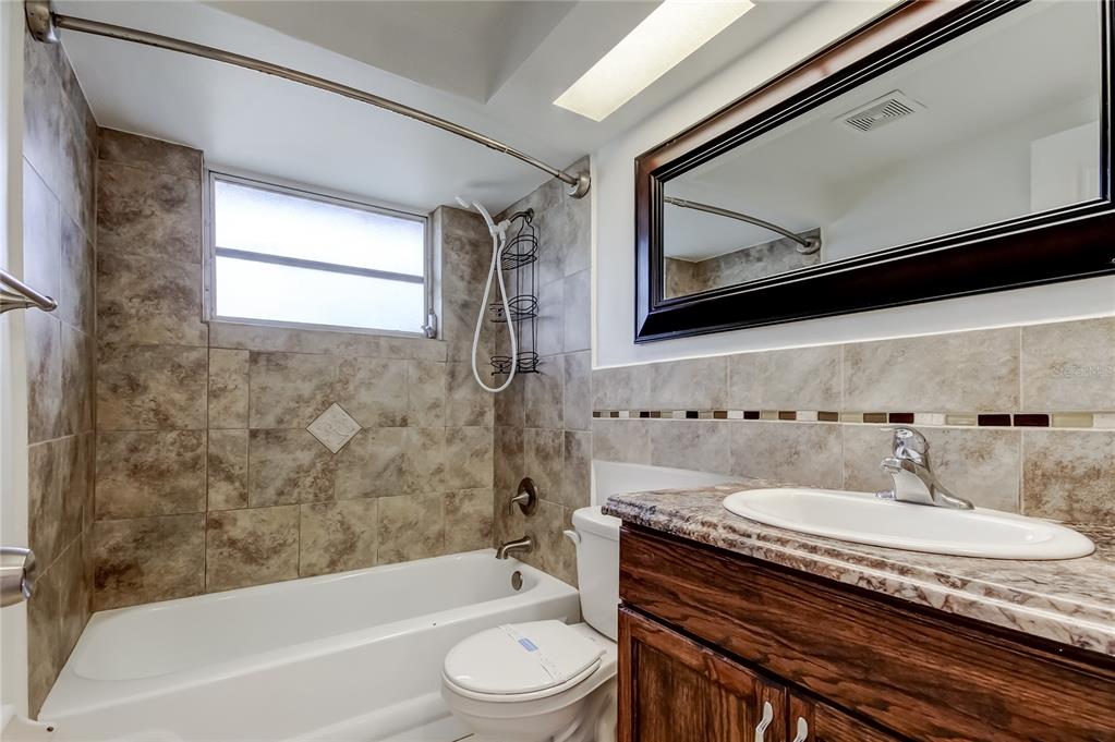 5753 Bantam Avenue New Port Richey, FL 34652 - Photo 26 of 47 a bathroom with a granite countertop bathtub shower sink vanity mirror and toilet