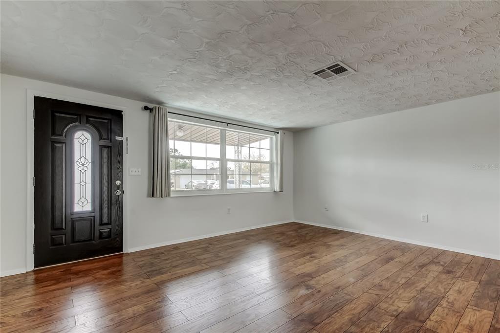 5753 Bantam Avenue New Port Richey, FL 34652 - Photo 5 of 47 a view of an empty room with wooden floor and a window