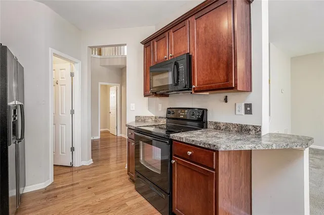 a kitchen with stainless steel appliances granite countertop a stove refrigerator sink and microwave