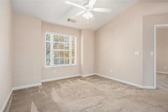 an empty room with windows and fan
