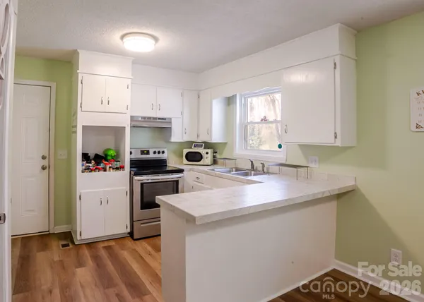 a kitchen with a sink a stove a refrigerator and white cabinets
