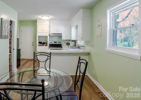 a kitchen with stainless steel appliances a dining table chairs and window