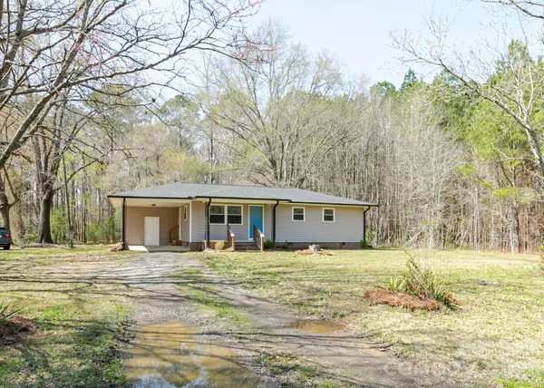 a front view of house with yard and trees in the background