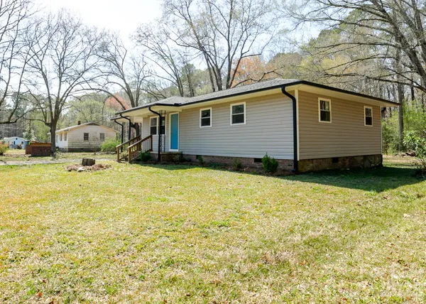 a backyard of a house with large trees and table and chairs