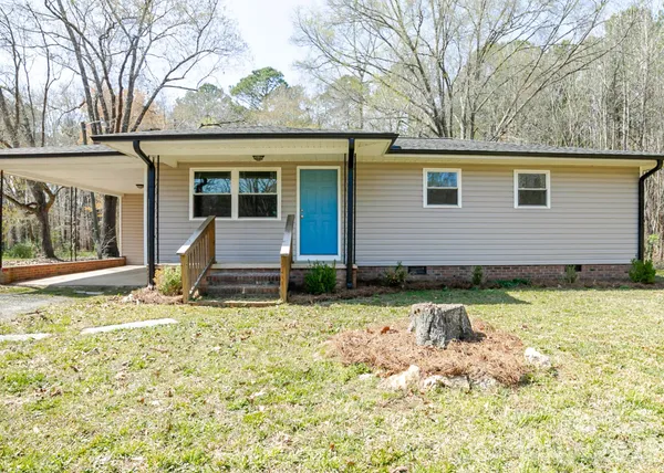 a view of a house with a yard and large tree