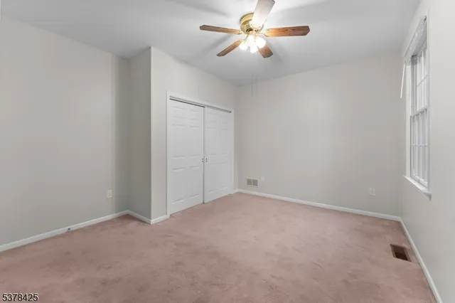an empty room with a window and a fan