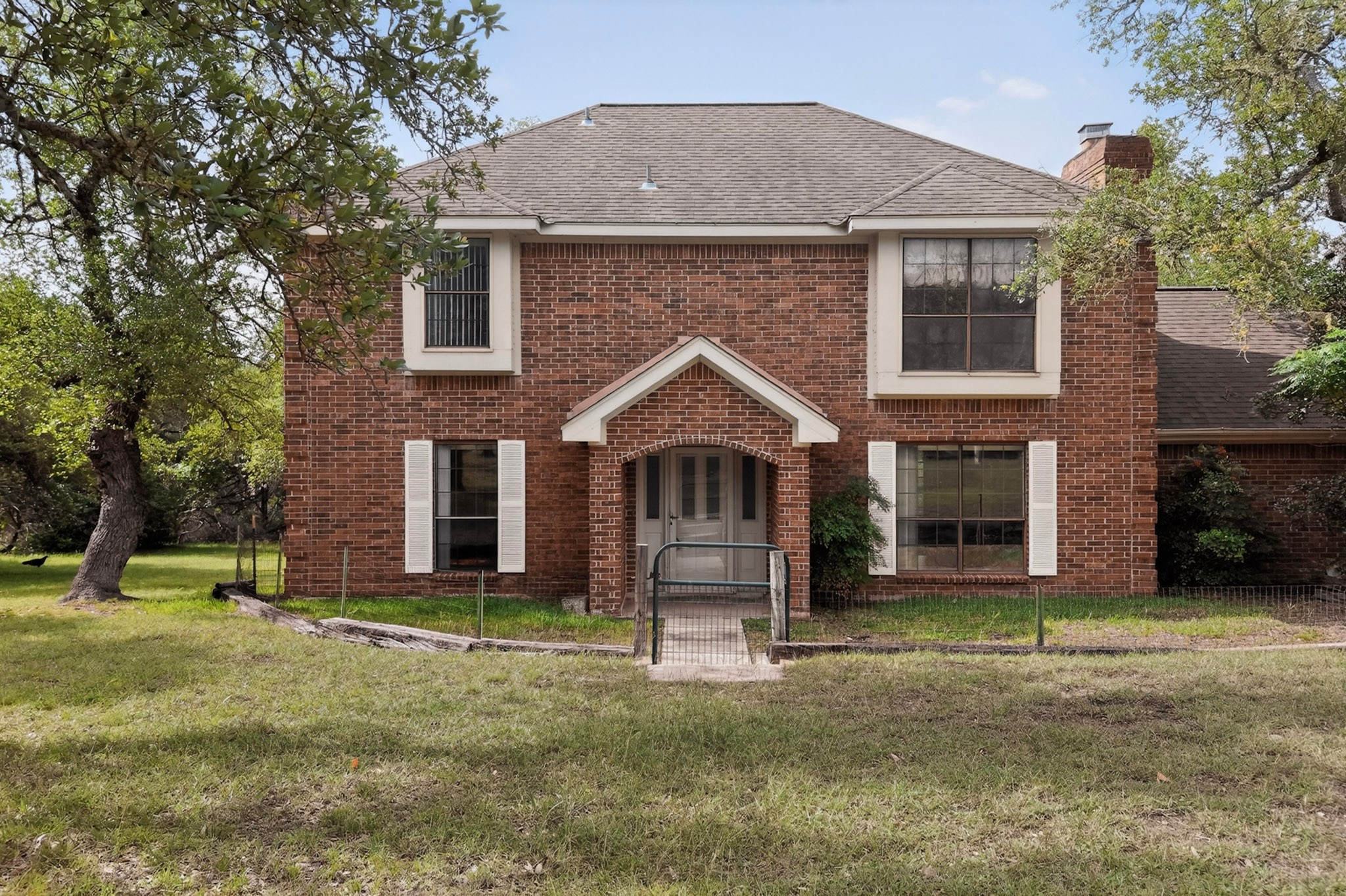 1003 Pier Branch Road Dripping Springs, TX 78620 - Photo 12 of 40 A classic brick exterior offers timeless appeal amidst mature trees and a verdant yard.