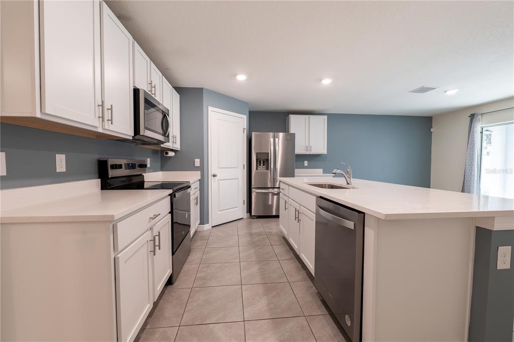 11272 Southeast 67th Circle Belleview, FL 34420 - Photo 16 of 24 a kitchen with a sink a stove top oven and white stainless steel appliances