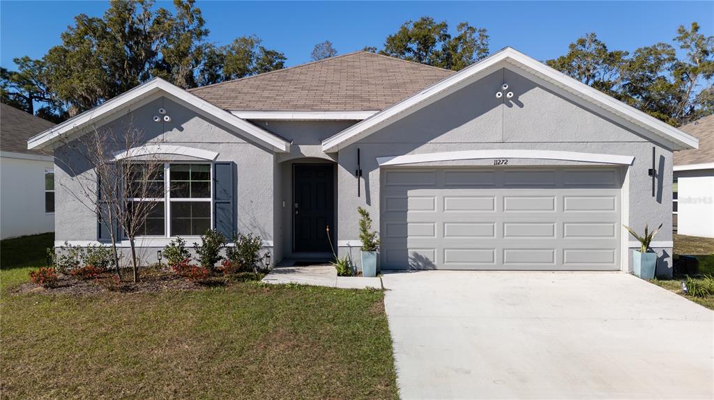 11272 Southeast 67th Circle Belleview, FL 34420 - Photo 2 of 24 a front view of a house with a yard and garage