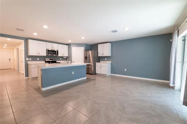 a large kitchen with stainless steel appliances granite countertop a stove a sink a microwave a counter top and cabinets