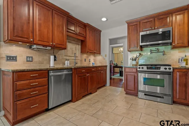 a kitchen with stainless steel appliances granite countertop a stove microwave and sink