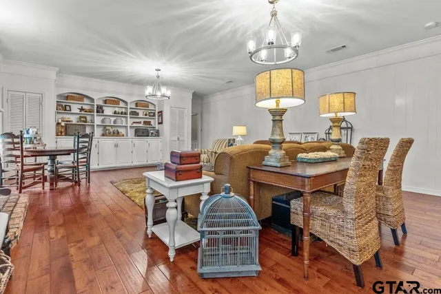 a dining room with furniture wooden floor a chandelier and a rug