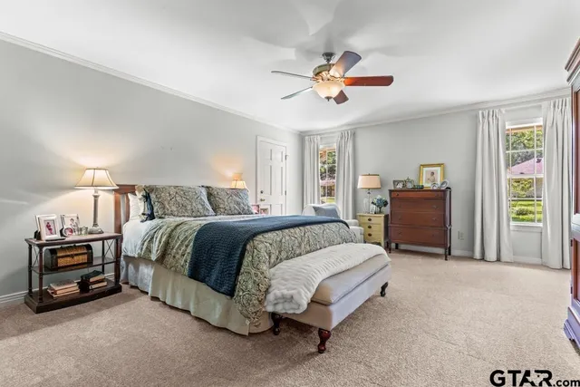 a spacious bedroom with a bed a chandelier and dresser