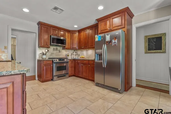 a kitchen with stainless steel appliances granite countertop a refrigerator and a stove top oven