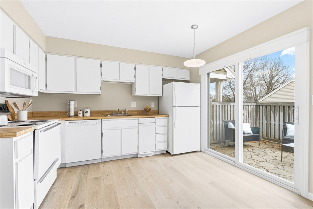 4 Drummer Boy Way, Unit 4 Lexington, MA 02420 - Photo 15 of 37 a kitchen with a refrigerator a stove and white cabinets with wooden floor