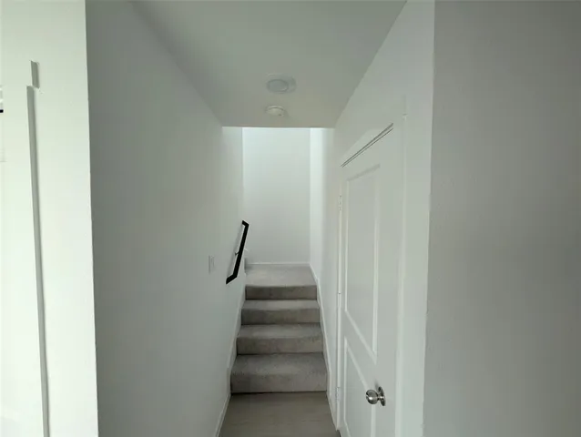 a view of staircase with white walls and white door
