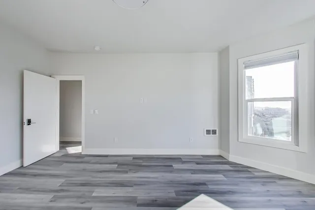 an empty room with wooden floor and windows
