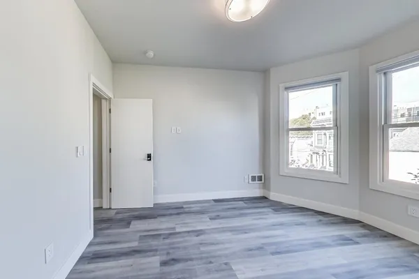a view of a room that has wooden floor and brick walls