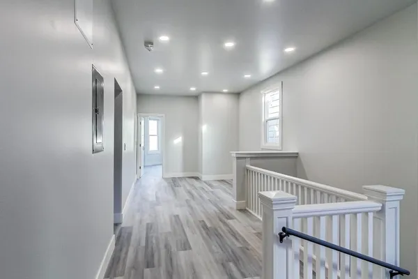 a view of empty room with wooden floor and fan