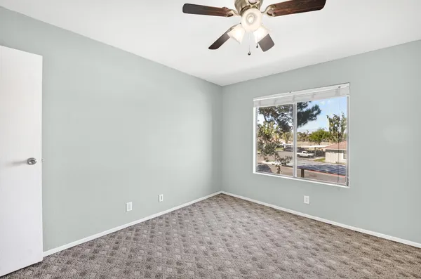 an empty room with window and ceiling fan