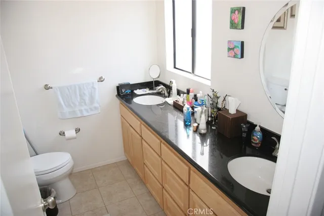 a bathroom with a granite countertop double vanity sink mirror and toilet