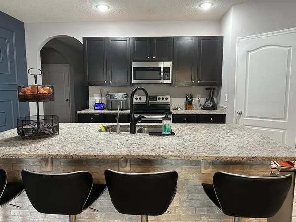 a kitchen with granite countertop a sink a stove and cabinets