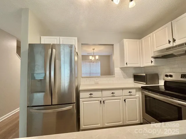 a kitchen with stainless steel appliances granite countertop a sink a stove and refrigerator