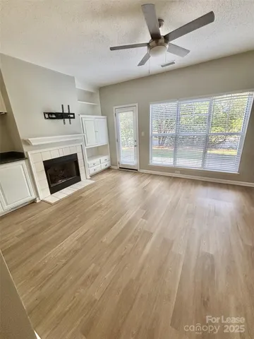 a view of a livingroom with a fireplace a ceiling fan and windows