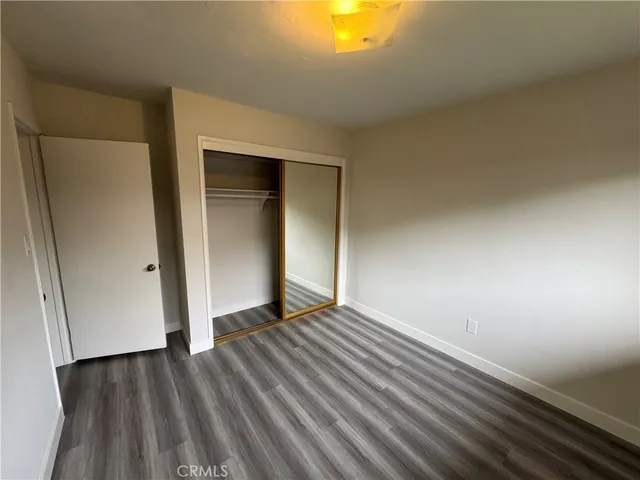 a view of an empty room with wooden floor and closet