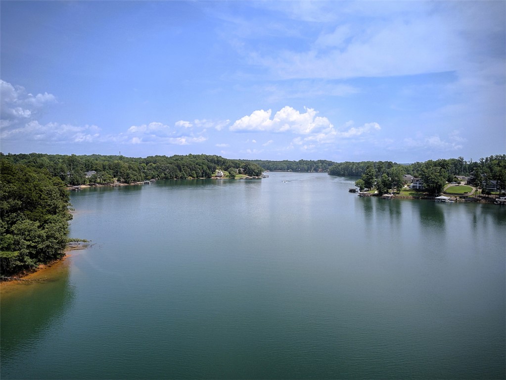Lot 24 Reservoir Road West Union, SC 29696 - Photo 43 of 46 An aerial panorama reveals a vast, serene lake with verdant shores, dotted with waterfront properties and a clear sky above.